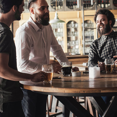 Three men talking and having drinks ata bar