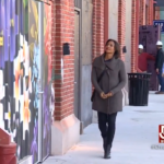 Woman walking down a sidewalk at Arsenal Yards