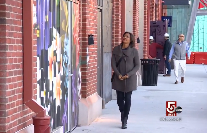 Woman walking down a sidewalk at Arsenal Yards