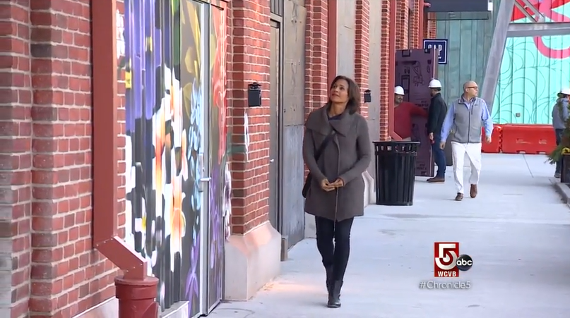 Woman walking down a sidewalk at Arsenal Yards