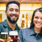 Friendly bartenders holding pints of beer