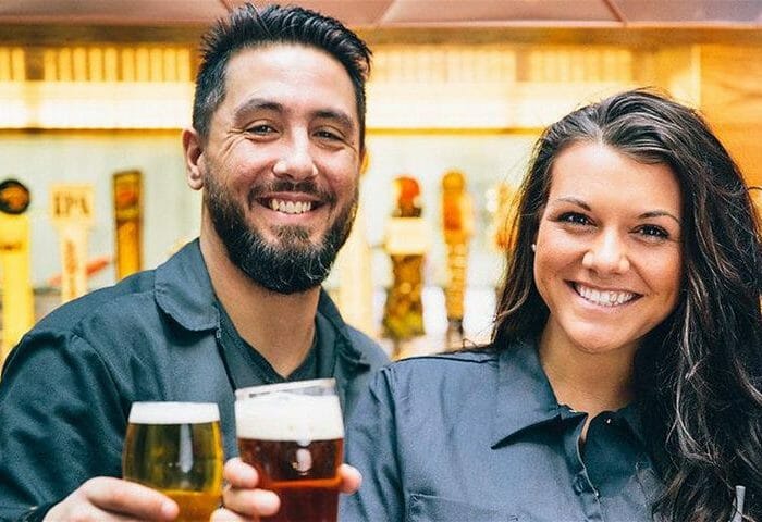 Friendly bartenders holding pints of beer