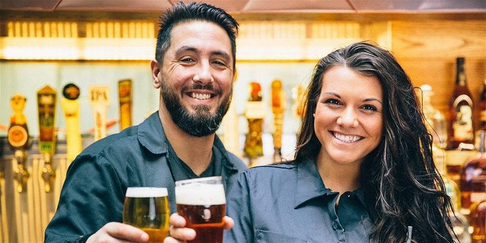 Friendly bartenders holding pints of beer