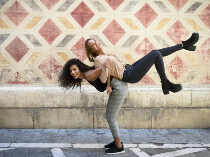 Laughing woman carrying her best friend piggyback